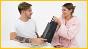woman holding black paper bag sitting in front of the man