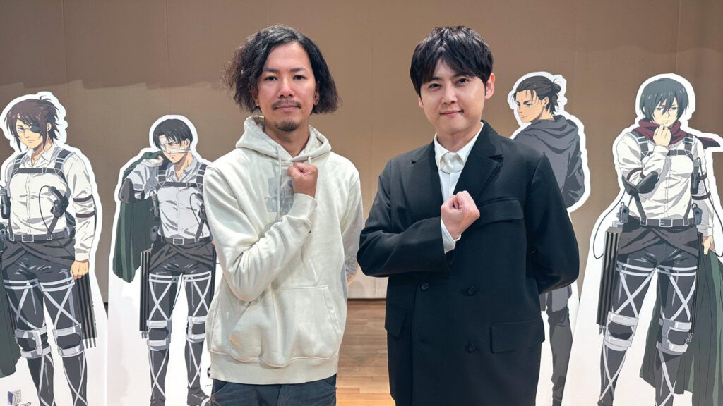 Attack on Titan creator Hajime Isayama and Eren Jaeger's voice actor Yuki Kaji at an AoT promotional event with the two doing the Survey Corps' Shinzou o Sasageyo pose