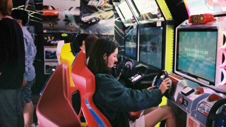 Girl playing driving game in Japanese arcade in Shimo-Kitazawa, Tokyo